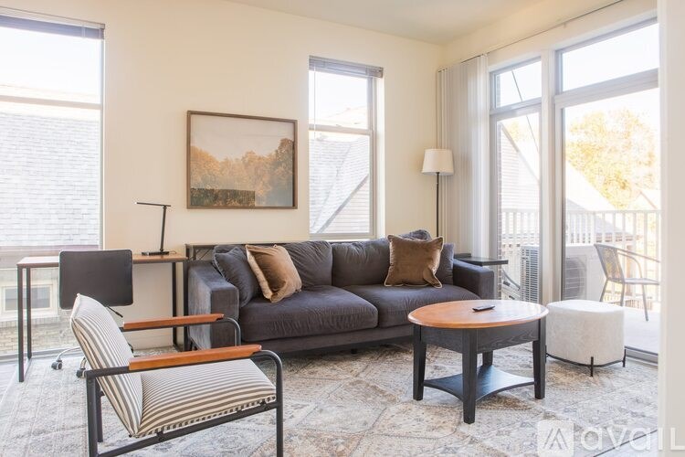 A living room with a grey couch, a striped chair, and a painting on the wall.