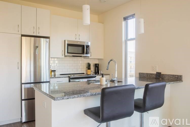 A kitchen with granite countertops and a stainless steel refrigerator.