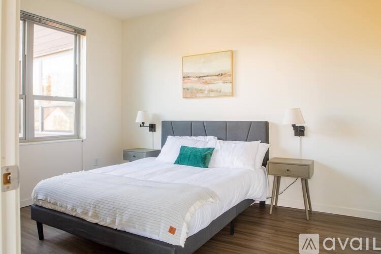 A bedroom with a large bed, a nightstand, and a painting on the wall.