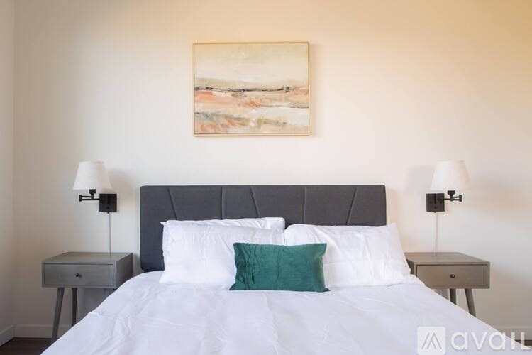 A bedroom with a large bed, two nightstands, and a painting on the wall.