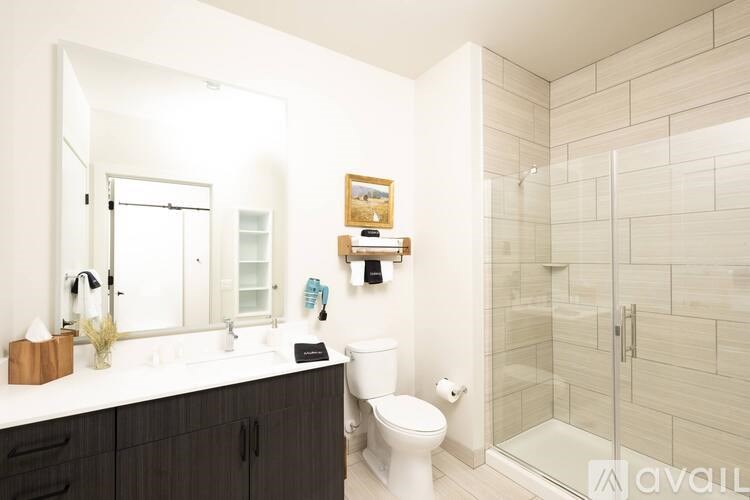 A bathroom with a toilet, sink, mirror, and shower.