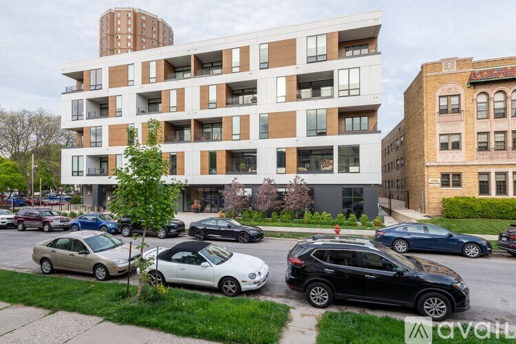 A modern apartment building with cars parked in front.