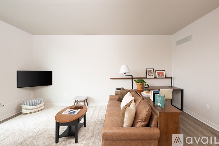 A living room with a brown couch, a wooden coffee table, and a flat screen TV mounted on the wall.