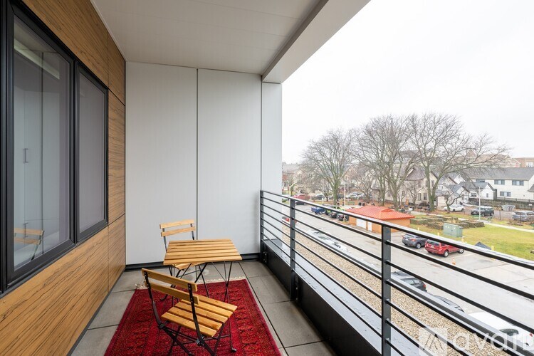 A balcony with a table and chairs overlooking a parking lot.