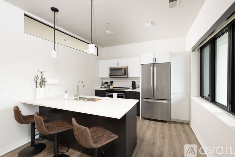 A modern kitchen with a white countertop and brown chairs.