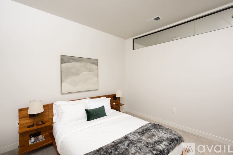 A bedroom with a bed, nightstand, and a painting on the wall.