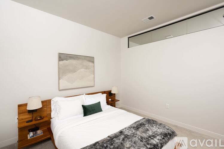 A bedroom with a bed, nightstand, and a painting on the wall.