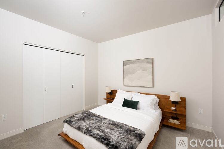 A bedroom with a bed, nightstand, and a painting on the wall.