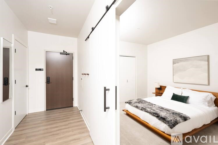 A bedroom with a bed, pillows, and a painting on the wall.