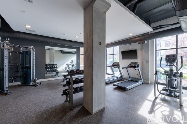 A spacious gym with a variety of equipment including a treadmill, weights, and a television.