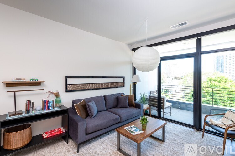 A living room with a grey couch, a coffee table, and a large window.