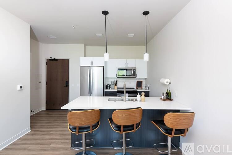 A kitchen with a bar stool and a fridge.