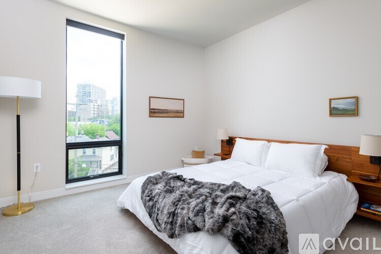A bedroom with a large bed and a window overlooking a cityscape.