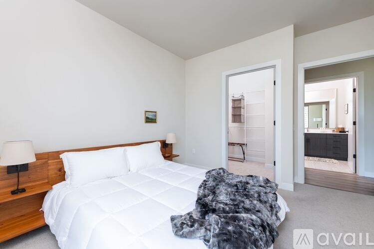 A bedroom with a large bed and a lamp on the nightstand.