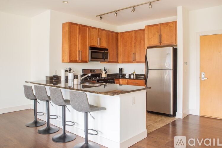 A kitchen with wooden cabinets and a white island with four grey barstools.