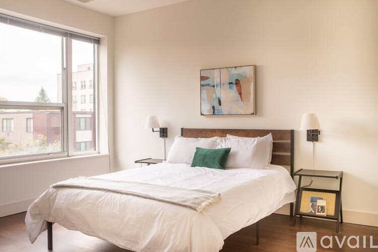 A bedroom with a large bed and a painting on the wall.