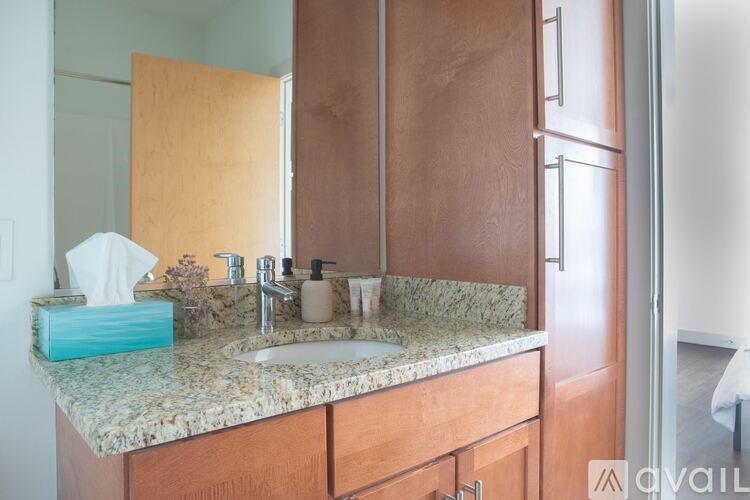 A bathroom with a marble countertop and wooden cabinets.
