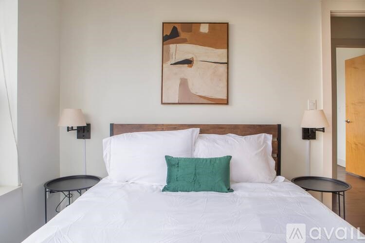 A bedroom with a large bed and a painting on the wall.