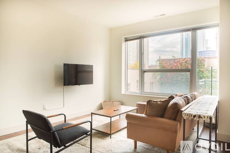 A living room with a black chair, a brown couch, and a flat screen TV mounted on the wall.