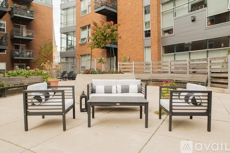A patio with a couch, two chairs and a table with a white cushion.