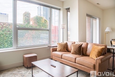 A living room with a brown couch and a coffee table in front of a large window.