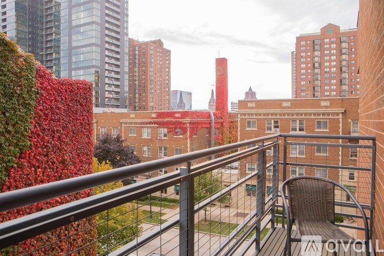 A balcony with a chair and a green wall with red flowers.