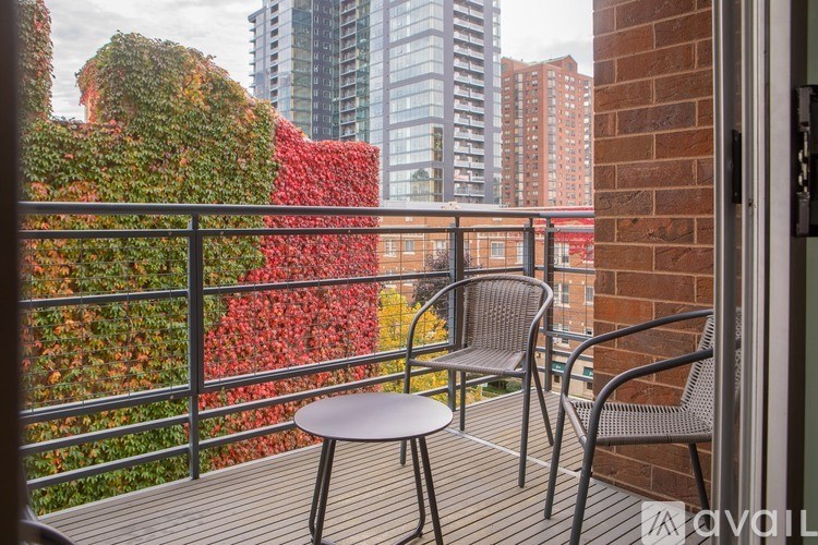 A balcony with a table and two chairs overlooking a green wall.