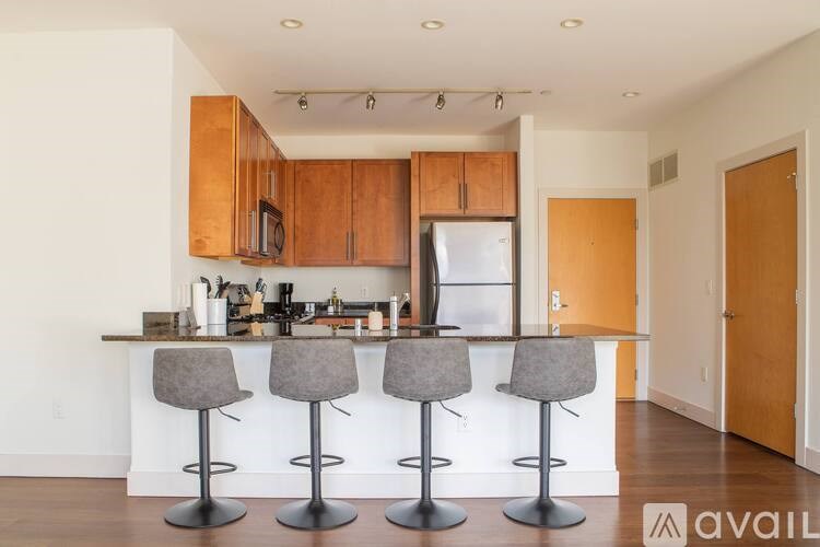 A kitchen with a white counter and bar stools.
