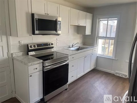A kitchen with white cabinets and appliances is available for rent.