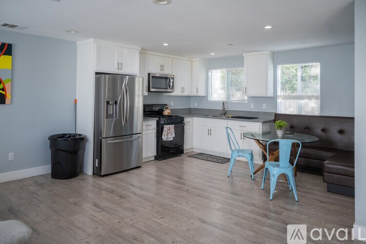 A kitchen with a refrigerator, microwave, and a dining table with chairs.