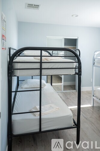 A black metal bunk bed with white bedding in a room.