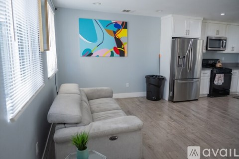 A living room with a grey couch and a painting on the wall.