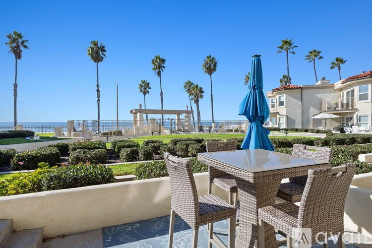 A patio with a table and chairs overlooking the ocean.