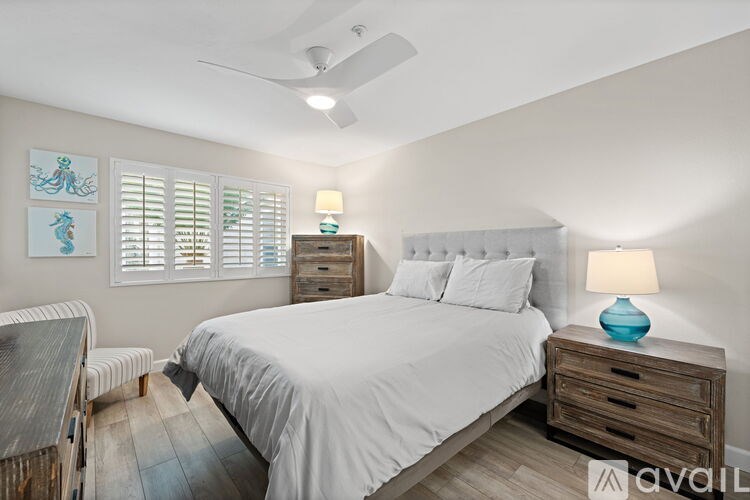 A bedroom with a bed, nightstand, and a ceiling fan.