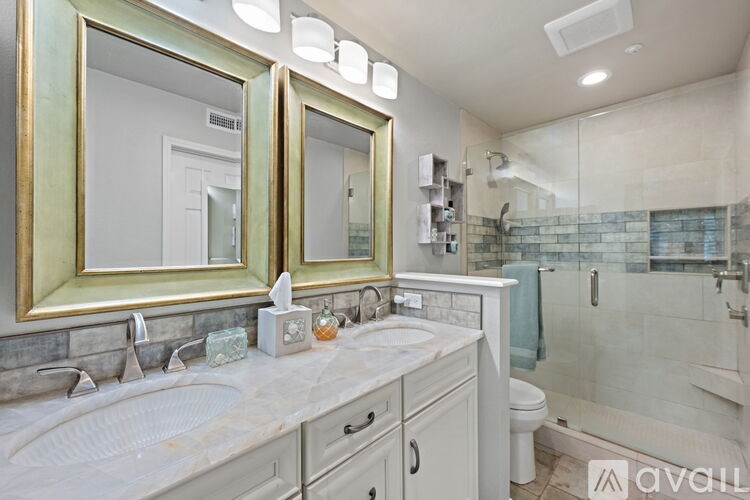 A bathroom with a double sink vanity and a glass shower stall.