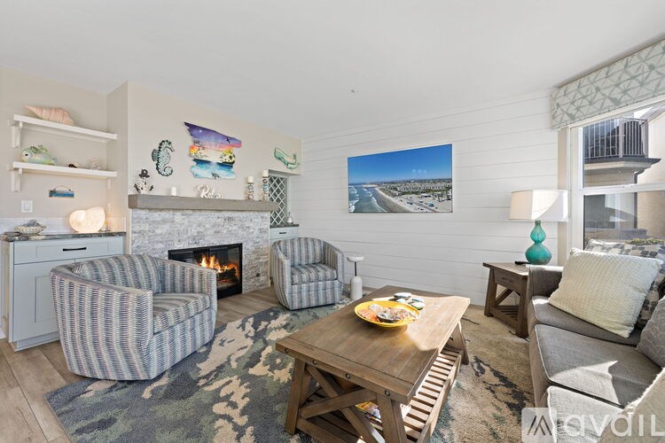 A living room with a fireplace and a painting of a beach scene on the wall.