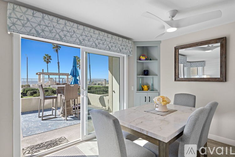 A dining room with a table set for two and a view of a pool area outside.