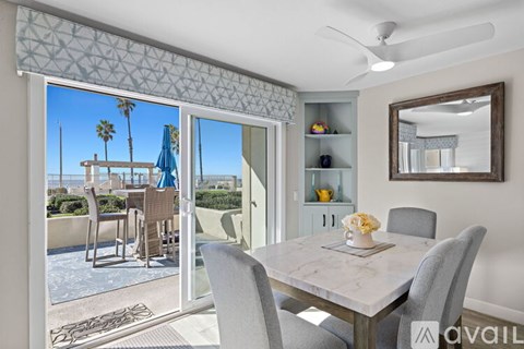 A dining room with a table set for two and a view of a pool area outside.