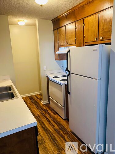 A kitchen with a white refrigerator, brown cabinets, and a sink.