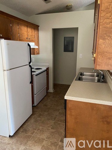 A kitchen with a white refrigerator, brown cabinets, and a sink.