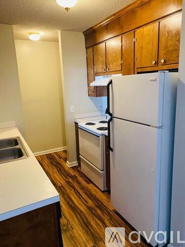 A kitchen with a white refrigerator, brown cabinets, and a sink.