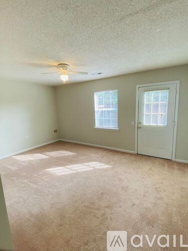 A room with a carpeted floor, a ceiling fan, and a window with blinds.