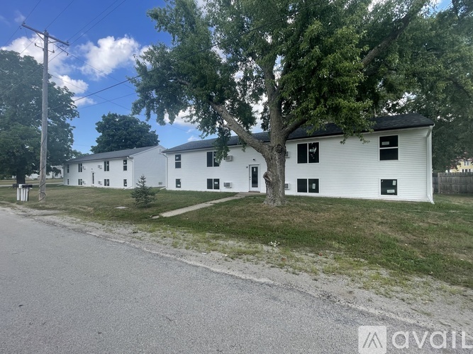 A white building with a tree in front of it.