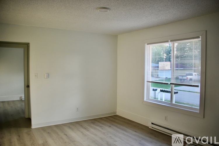 A room with a window showing a street view and a wooden floor.