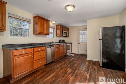 A kitchen with wooden cabinets and a black refrigerator.