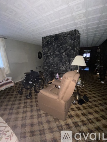 A room with a chair, a lamp, and a wheelchair.