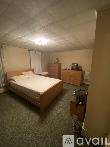 A bedroom with a bed, nightstand, and chair.