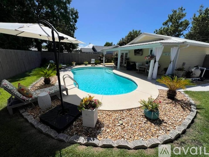 A pool surrounded by a gravel bed and a white umbrella.