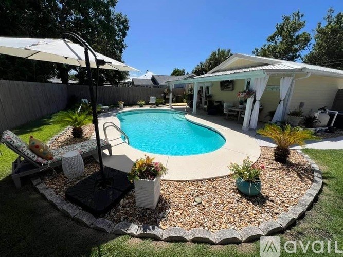 A pool surrounded by a gravel bed and a white umbrella.