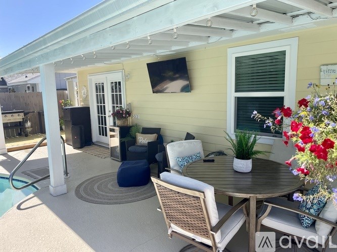 A patio with a table, chairs, and a television mounted on the wall.